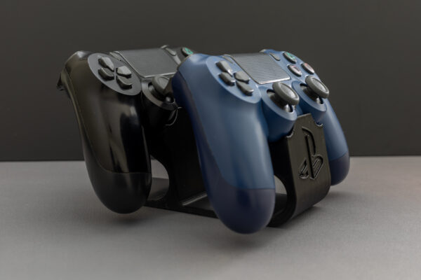 Two PlayStation 4 controllers (one black, one blue) mounted on 3D printed black plastic dual controller stand