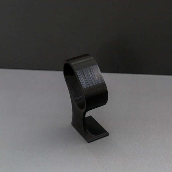 Close-up of the empty black 3D-printed watch stand, highlighting its layer lines and curved hook design for secure watch placement.